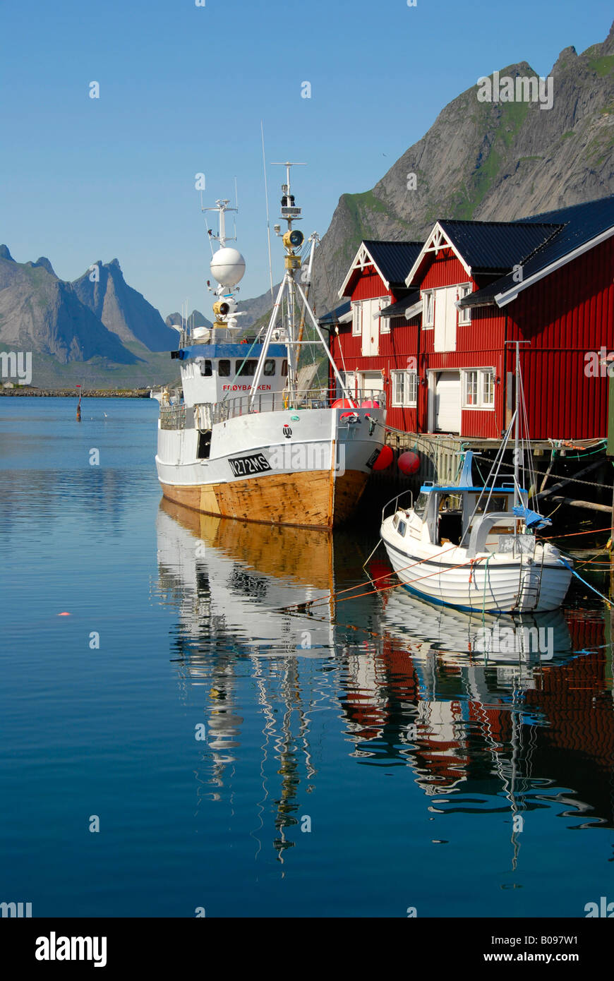 Vue sur les bateaux dans le port, en bois rouge "rorbu" des maisons, et les montagnes de l'Île Moskenesoya, Hamnøy, Reine, Lofoten Archipelag Banque D'Images
