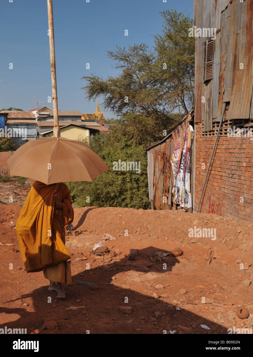 Monk à pied de temple, à l'aide d'un parapluie à l'ombre du soleil de midi, phnom penh , Cambodge Banque D'Images