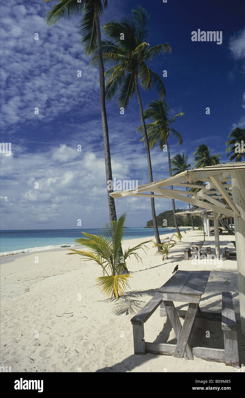 Plage de sable blanc de la mer bleu-soleil table en bois et banquette Blackbird ciel bleu palmiers Hills PLAGE DE DARKWOOD ANTIGUA Banque D'Images