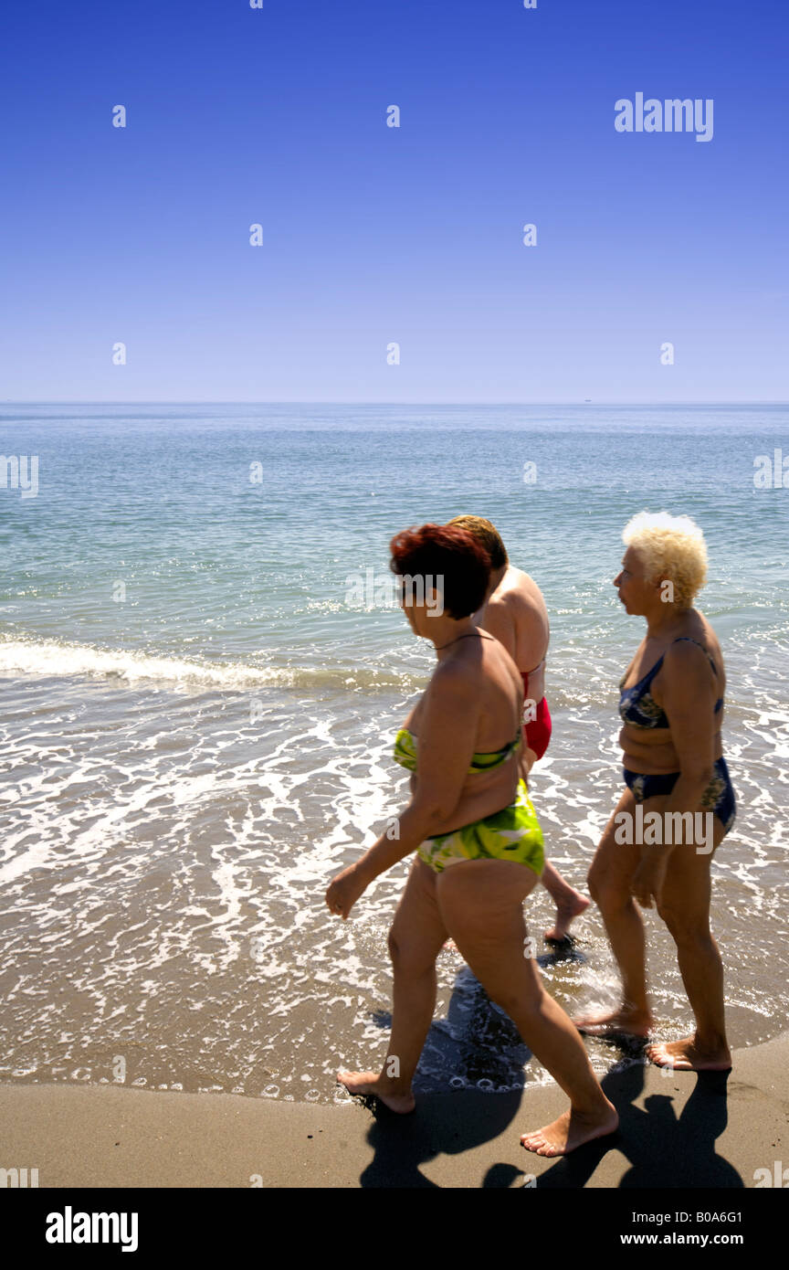 Trois femmes d'âge moyen dodus en bikini la marche sur la plage, mer Méditerranée, Torremolinos, Costa del Sol, Espagne Banque D'Images