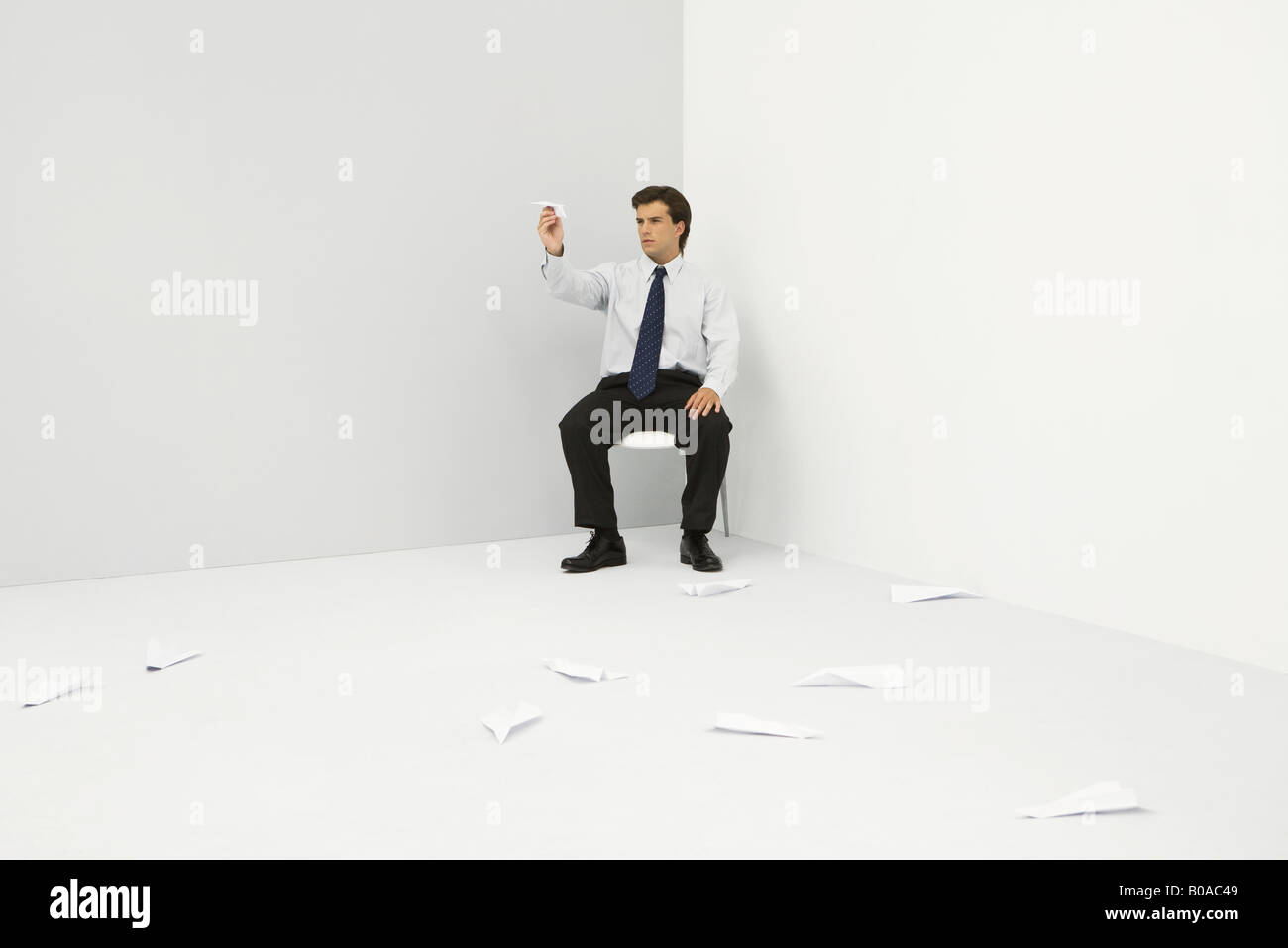 Hommes assis dans le coin, de lancer des avions de papier Banque D'Images