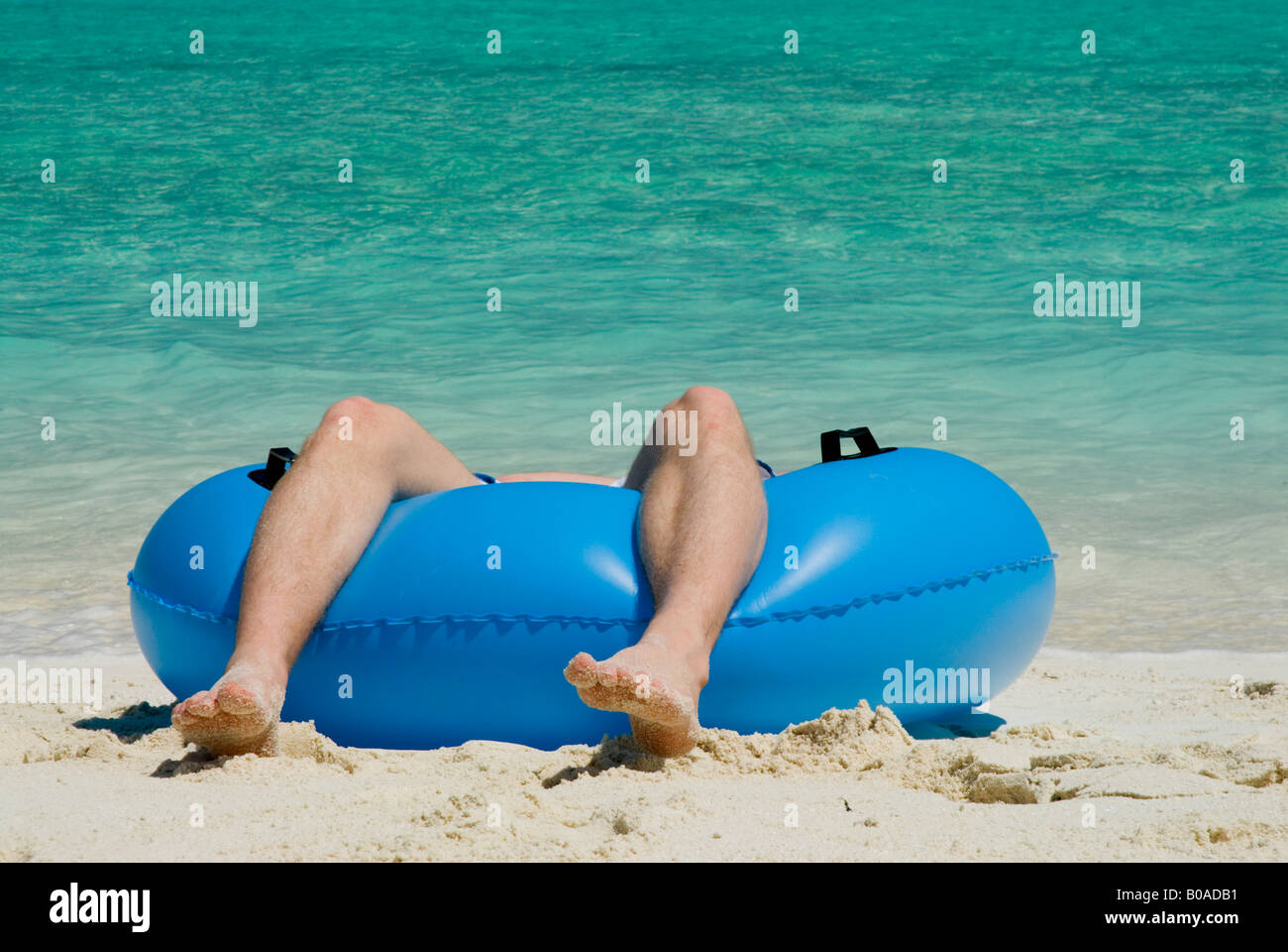 Une personne détendue relax repose dans le tube en caoutchouc pieds seulement bleu ciel bleu mer visibles Luc M. Hanna Banque D'Images