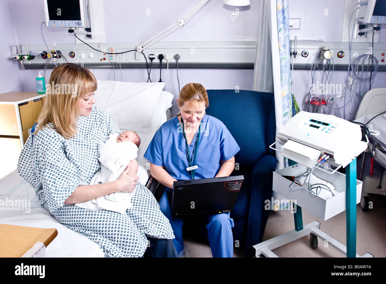 Maman avec son nouveau-né avec une sage-femme pendant qu'elle utilise le nouveau matériel informatique pour vérifier le nouveau-né Banque D'Images