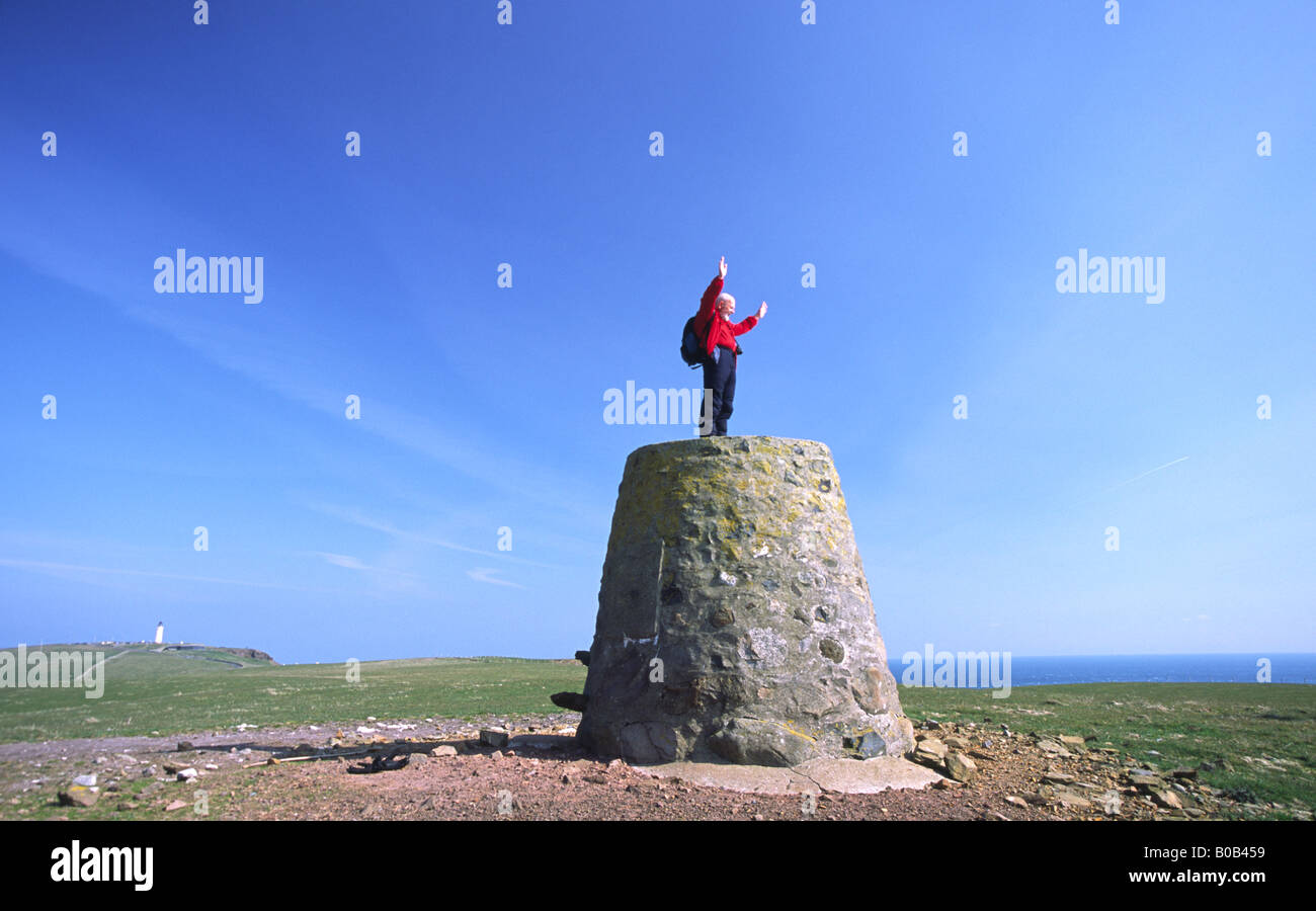 Des promenades à pied le Mull of Galloway walker sur Kennedy's Cairn avec derrière le phare de Rhins of Galloway, Scotland UK Banque D'Images