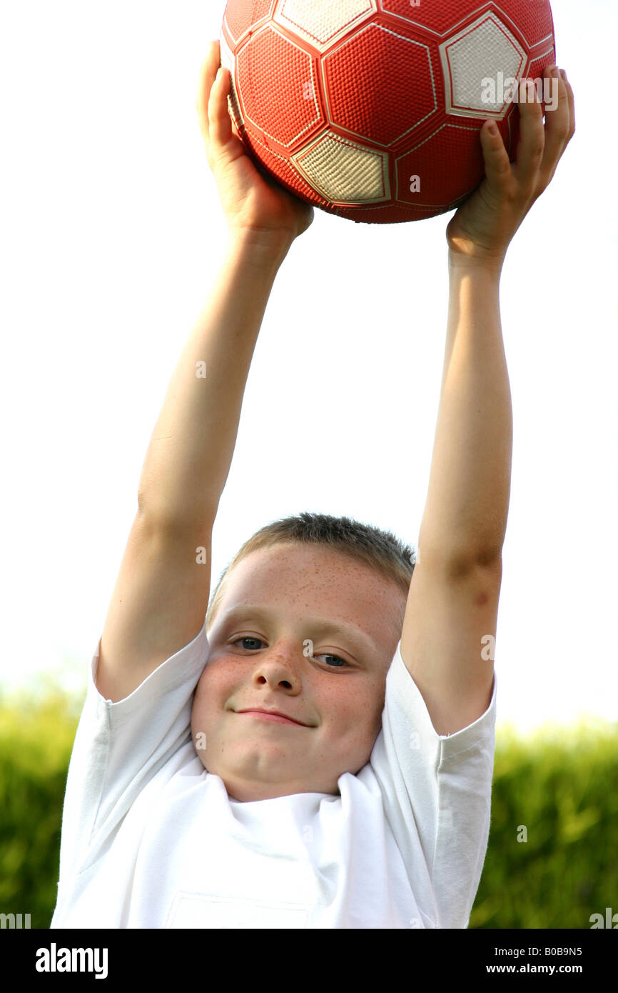 Un garçon qui s'étend pour attraper un ballon de football Banque D'Images
