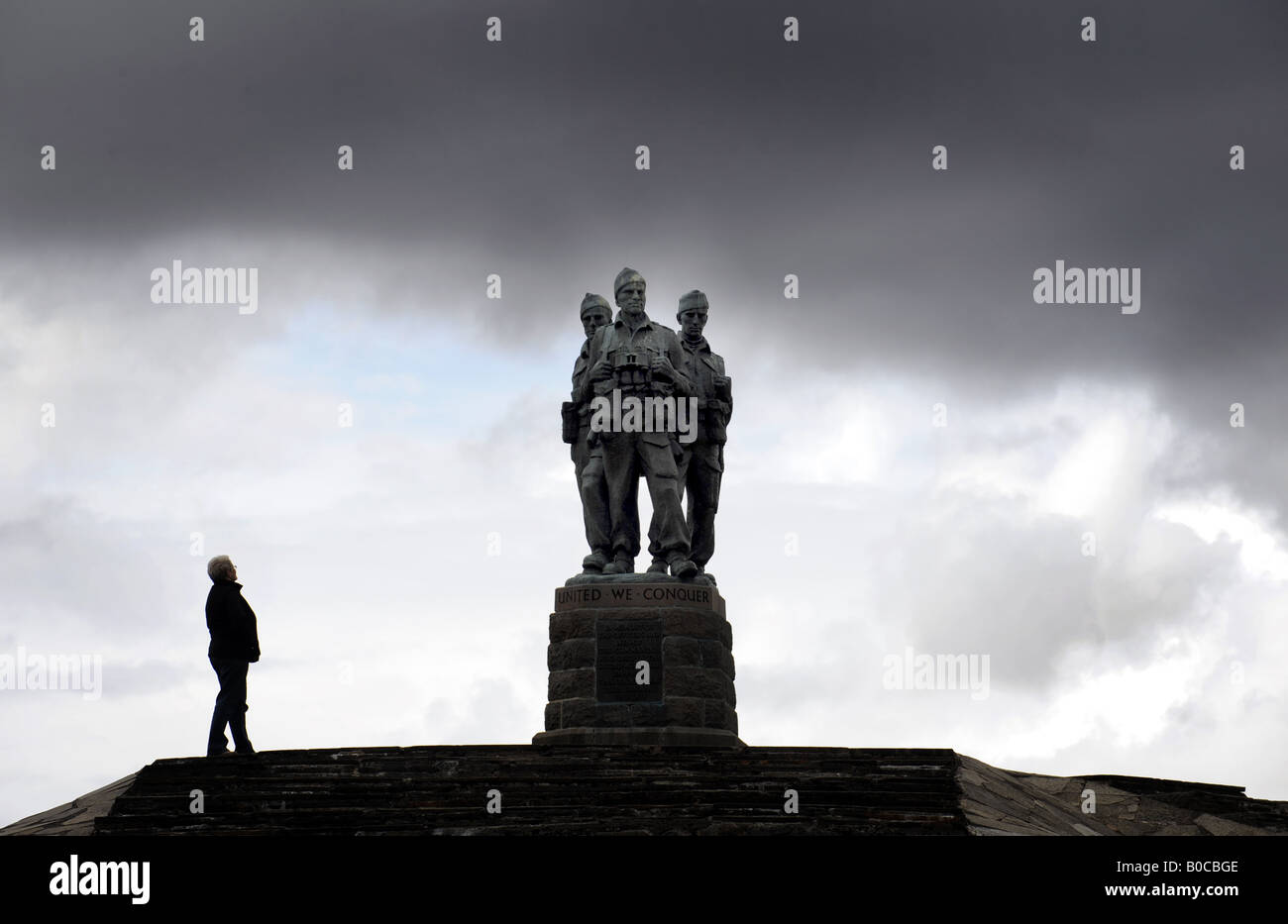 Un touriste SE PENCHE SUR LE RÉGIMENT COMMANDO WAR MEMORIAL SOUS UN CIEL NOIR À SPEAN BRIDGE, PRÈS DE FORT WILLIAM en Ecosse, Royaume-Uni. Banque D'Images