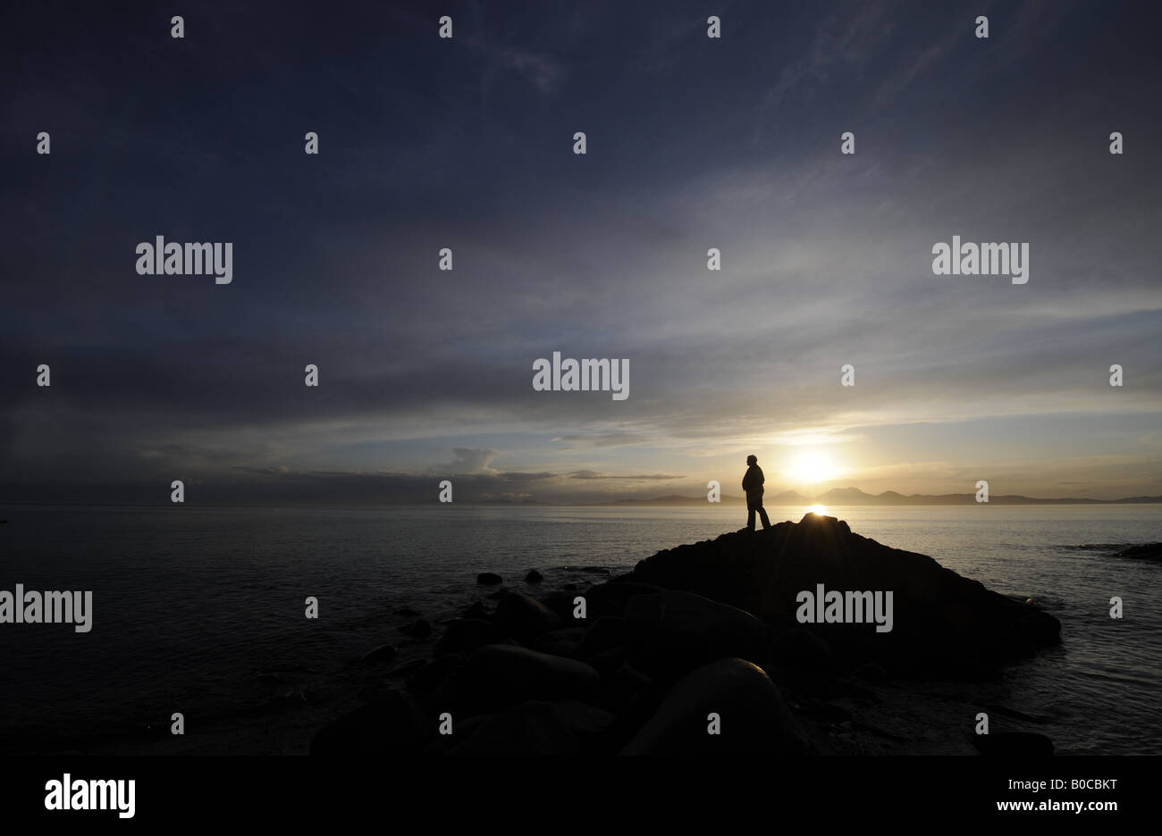 Une personne regarde un coucher de soleil spectaculaire SUR LA CÔTE DE KINTYRE À L'ENSEMBLE DE L'ÎLE DE JURA, Ecosse, Royaume-Uni. Banque D'Images