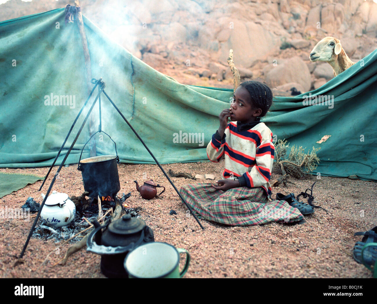 Une fille est Touareg qui gardaient la casserole, préparer le petit-déjeuner dans un petit établissement, dans l'Ahaggar mountains dans le sud de l'Algérie Banque D'Images