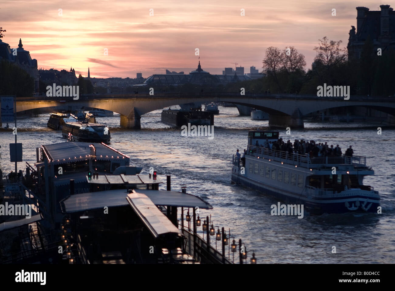 Les bateaux d'excursion au coucher du soleil sur la Seine et le Musée d'Orsay et le Grand Palais en silhouette. Vue sur le pont de Caroussel Banque D'Images