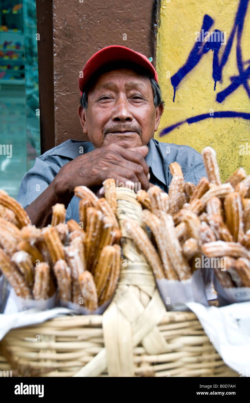 Man selling churros au coin d'une rue à Puebla, au Mexique. Goûter un peu comme une version plus croustillante pâte d'un écrou. Très doux ! Banque D'Images