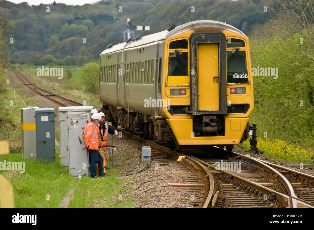 Pays de Galles arriva DMU train sur la voie unique de la ligne de côte Cambrian passant d'un groupe d'ingénieurs qui travaillent sur les points Banque D'Images