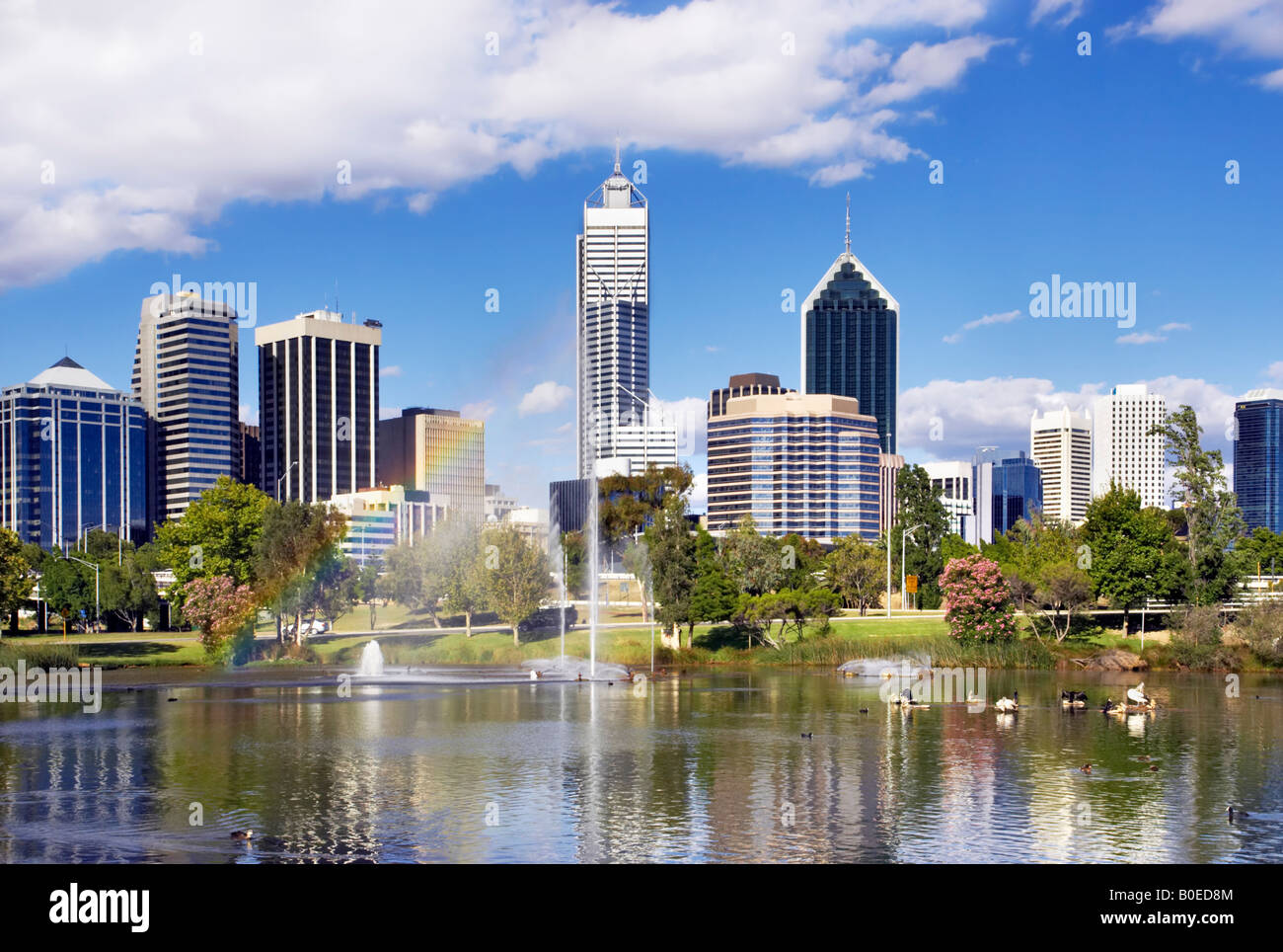 Les gratte-ciel de Perth s'élevant au-dessus d'un parc du centre-ville. Un arc-en-ciel apparaît dans la fontaine à jets. Perth, Australie Banque D'Images