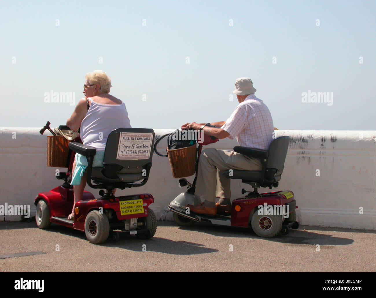 Couple de personnes âgées à la mer se déplacer sur les scooters motorisés sur prêt d'Shopmobility West Sussex Bognor Regis Banque D'Images