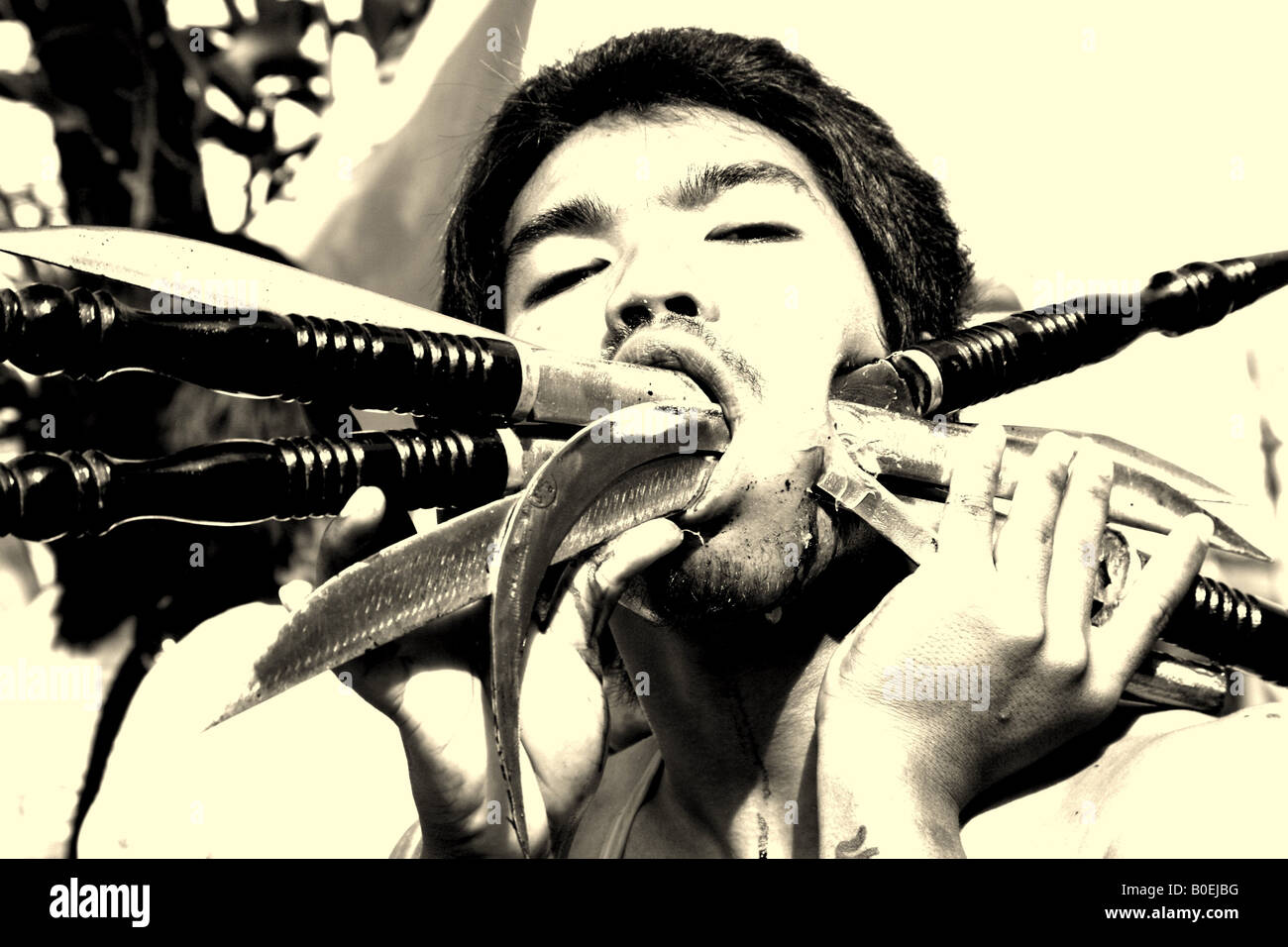 Homme avec six ou sept couteaux à travers sa joue, festival végétarien de Phuket Banque D'Images