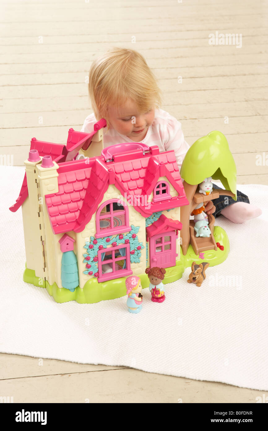 Une petite fille joue avec un jouet rose dolls house Banque D'Images