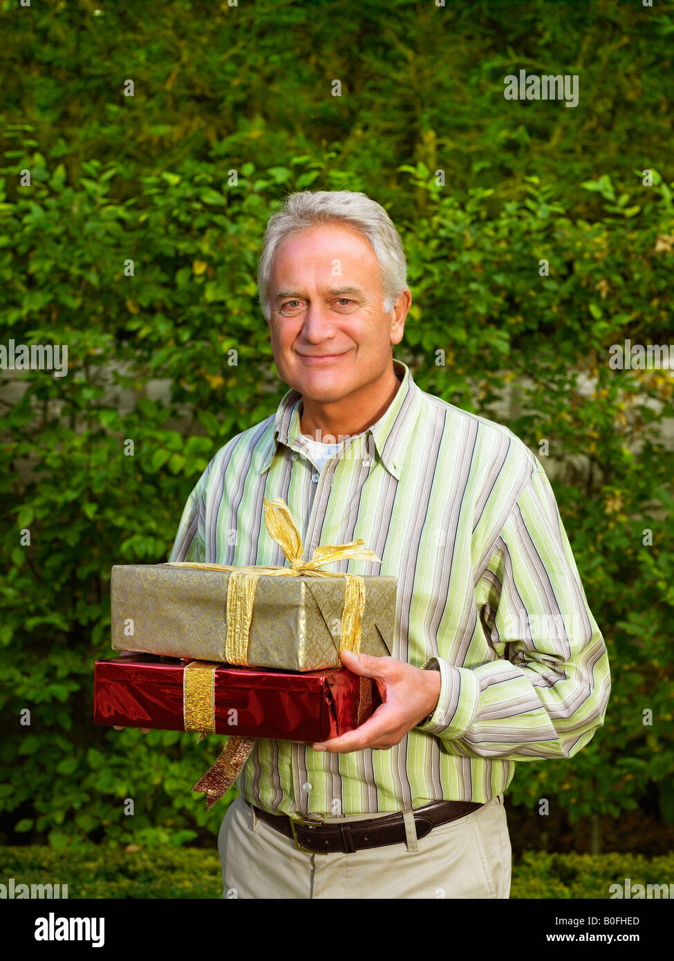 Senior man holding presents Banque D'Images