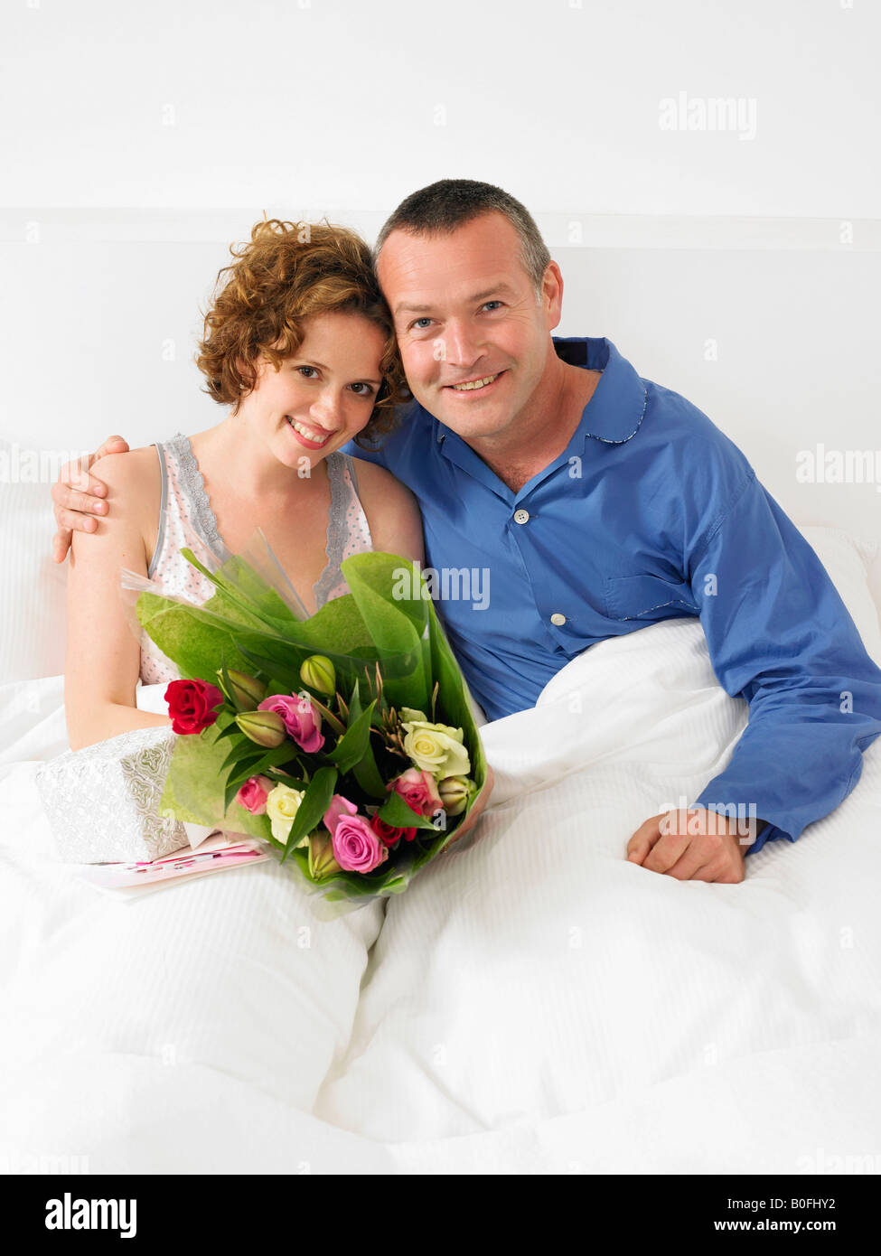 L'homme et la femme au lit avec des fleurs Banque D'Images