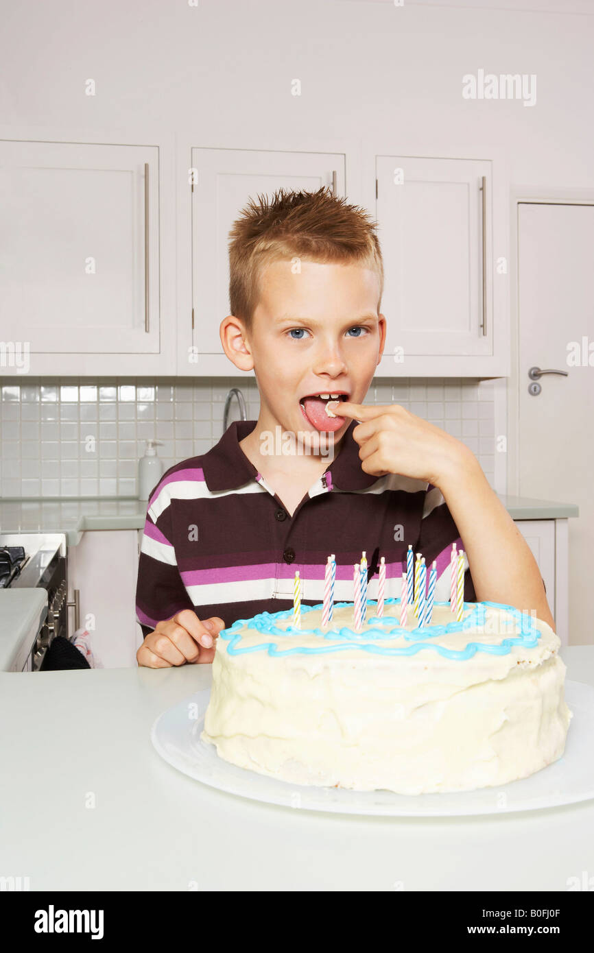 Boy licking glaçage à gâteau Banque D'Images