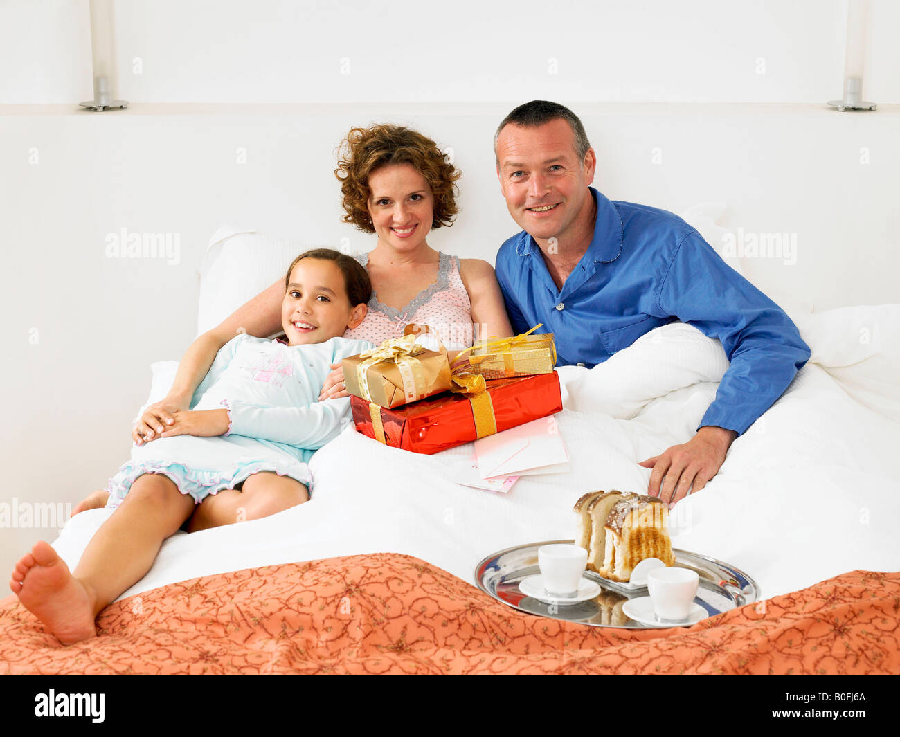 Fille sur le lit avec sa mère et à son père Banque D'Images