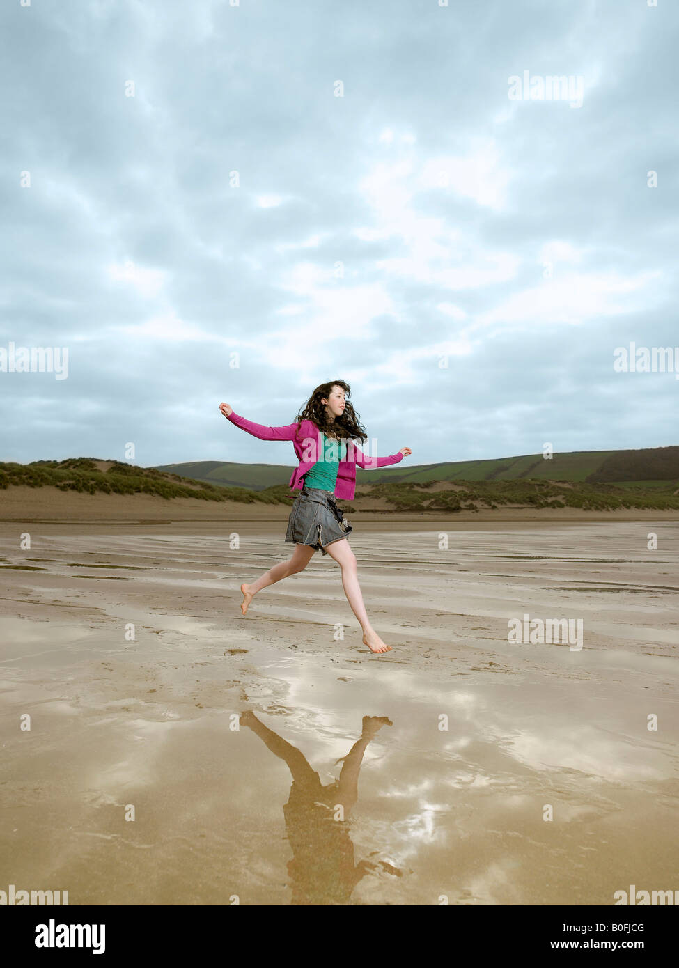 Jeune femme sautant sur la plage Banque D'Images