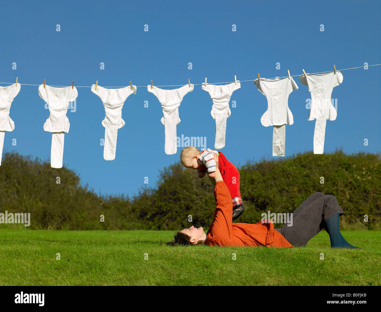 Mother lying on grass holding up baby Banque D'Images