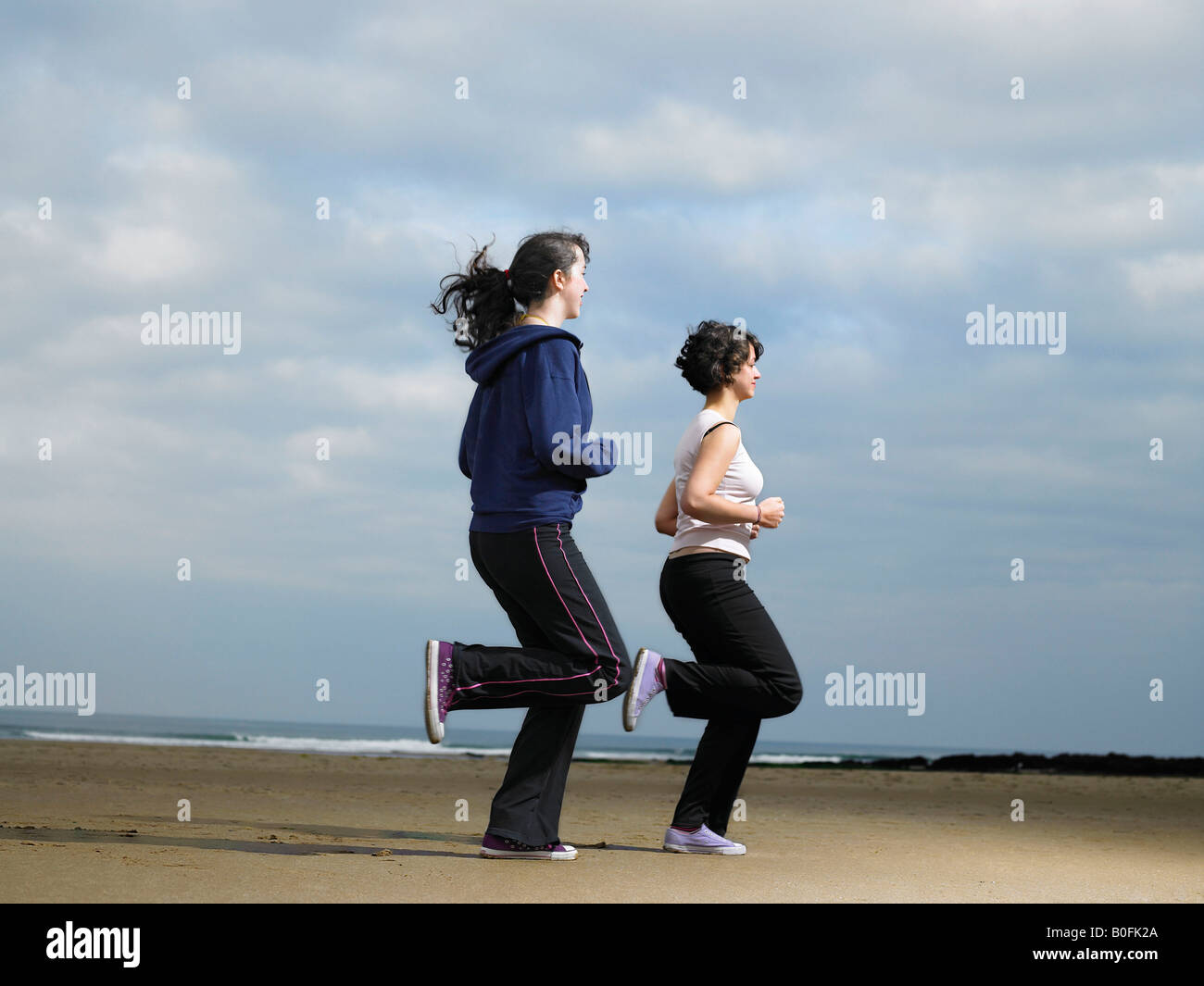 Deux jeunes femmes jogging on beach Banque D'Images
