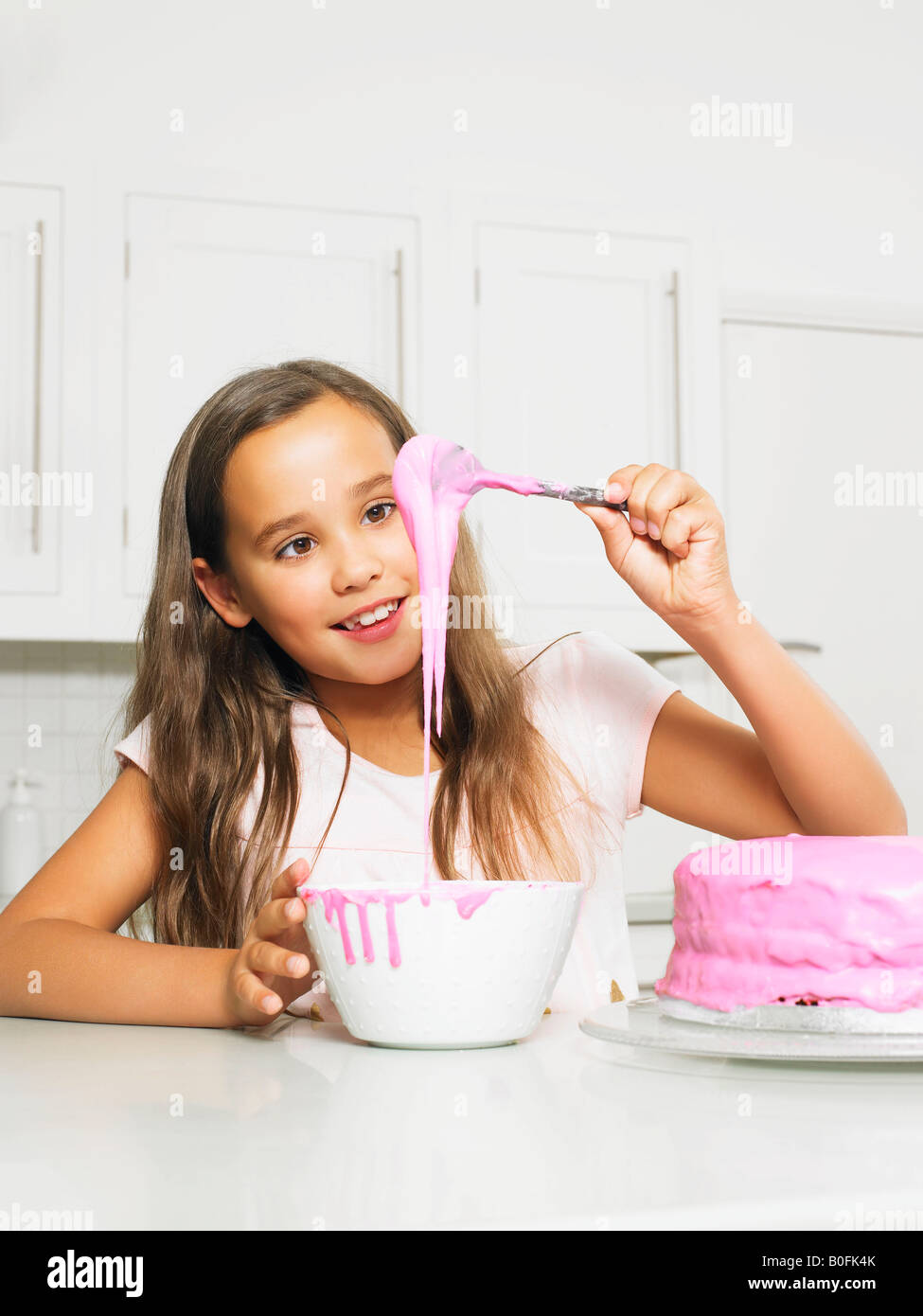 Girl (8-10) decorating cake with icing Banque D'Images