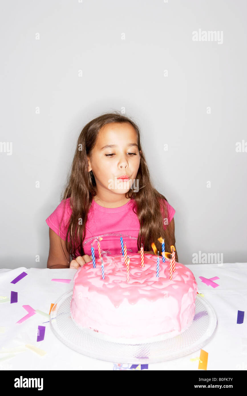 Girl blowing out candles on cake Banque D'Images