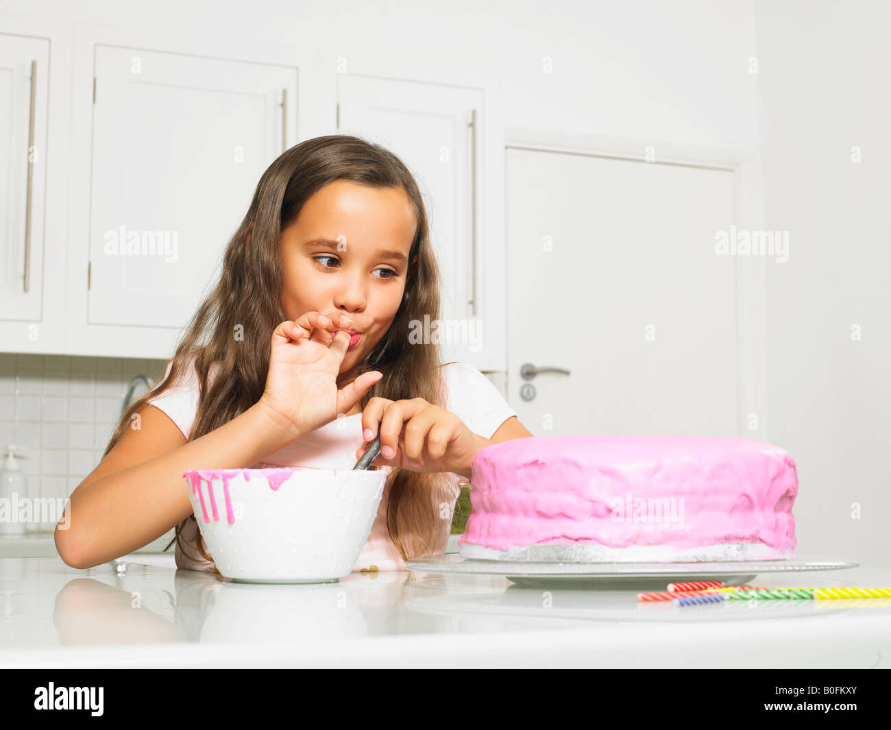 Girl licking gâteau glacé par doigt Banque D'Images