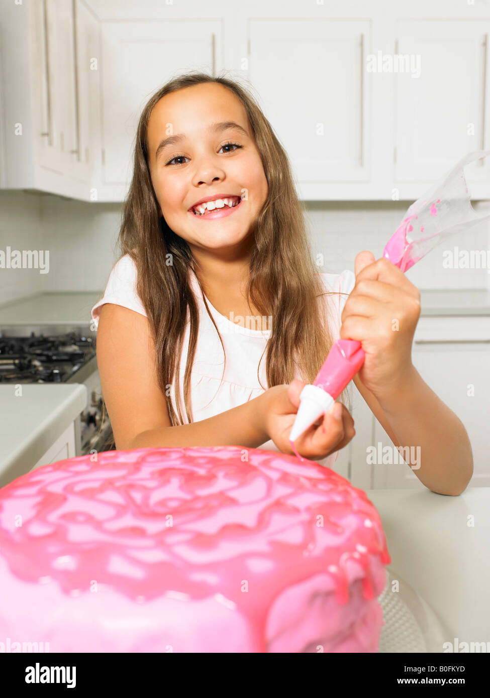 Girl (8-10) gâteau de givrage Banque D'Images