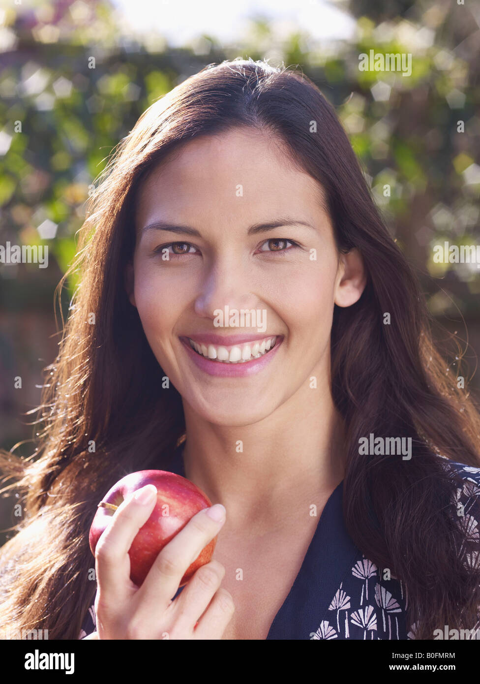 Young woman smiling and holding apple Banque D'Images