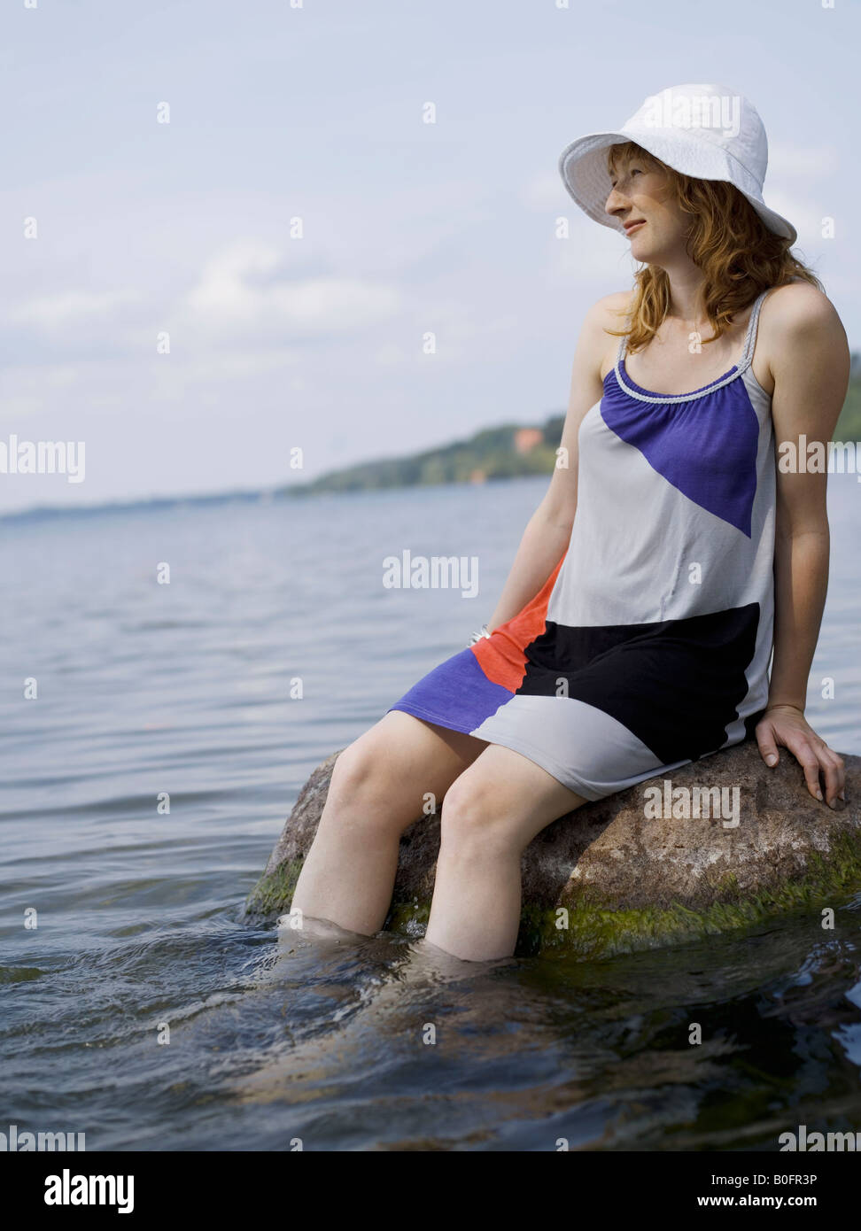 Femme assise sur un rocher dans l'eau Banque D'Images