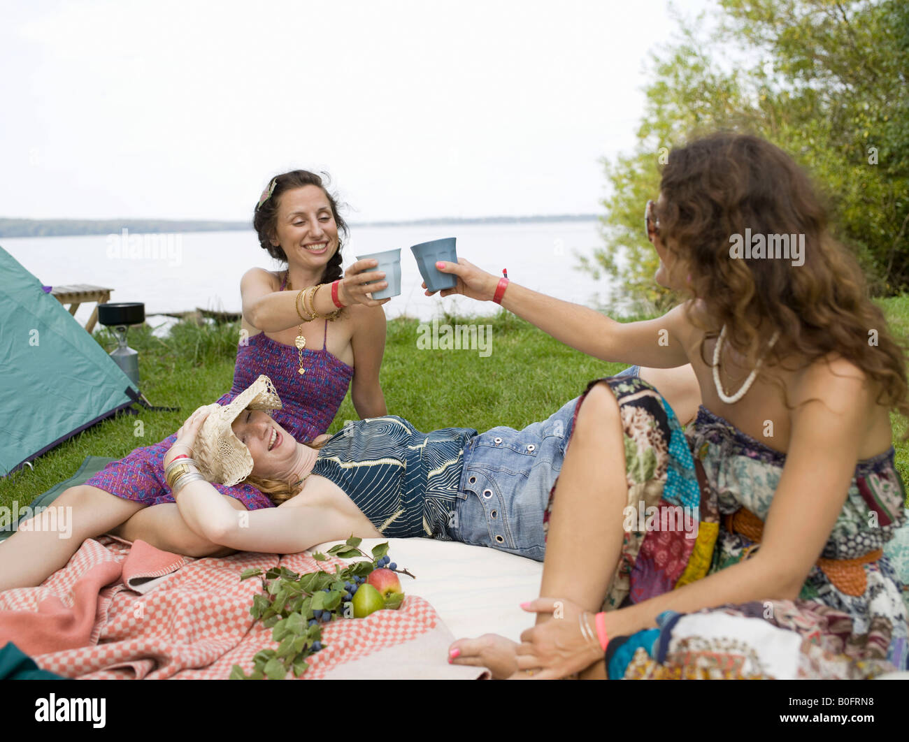 Trois femmes sur couverture en face de tente Banque D'Images