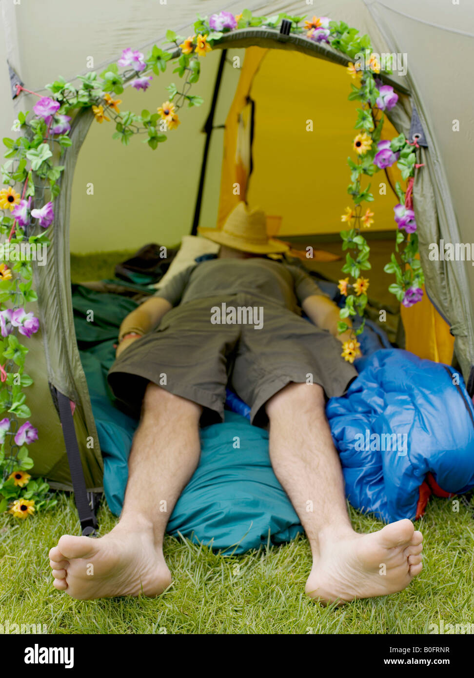 Man sleeping in tent avec chapeau sur le visage Banque D'Images