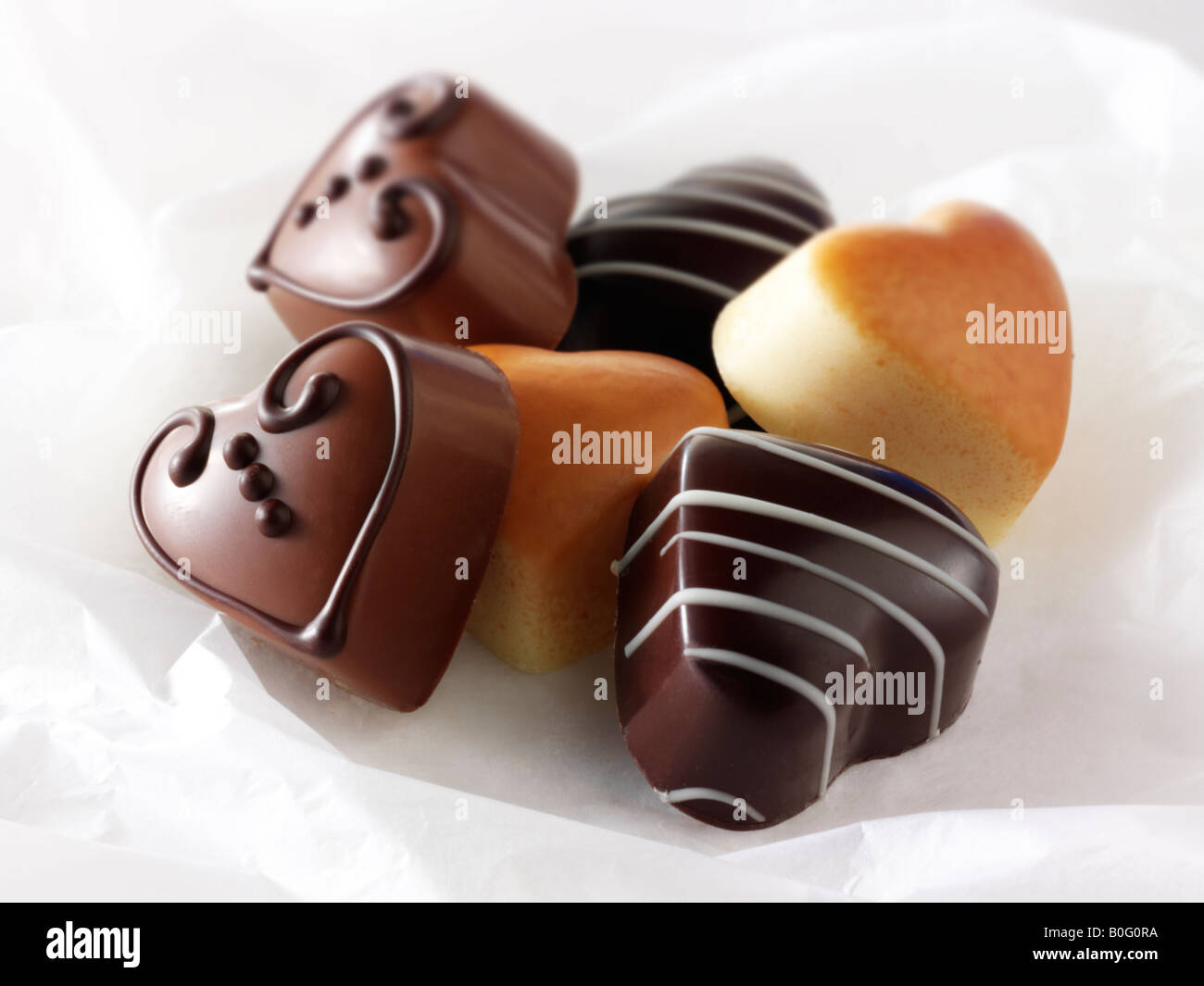 Studio photo de l'alimentation individuelle fait main en forme de coeur chocolats décorés sur un fond blanc. Banque D'Images
