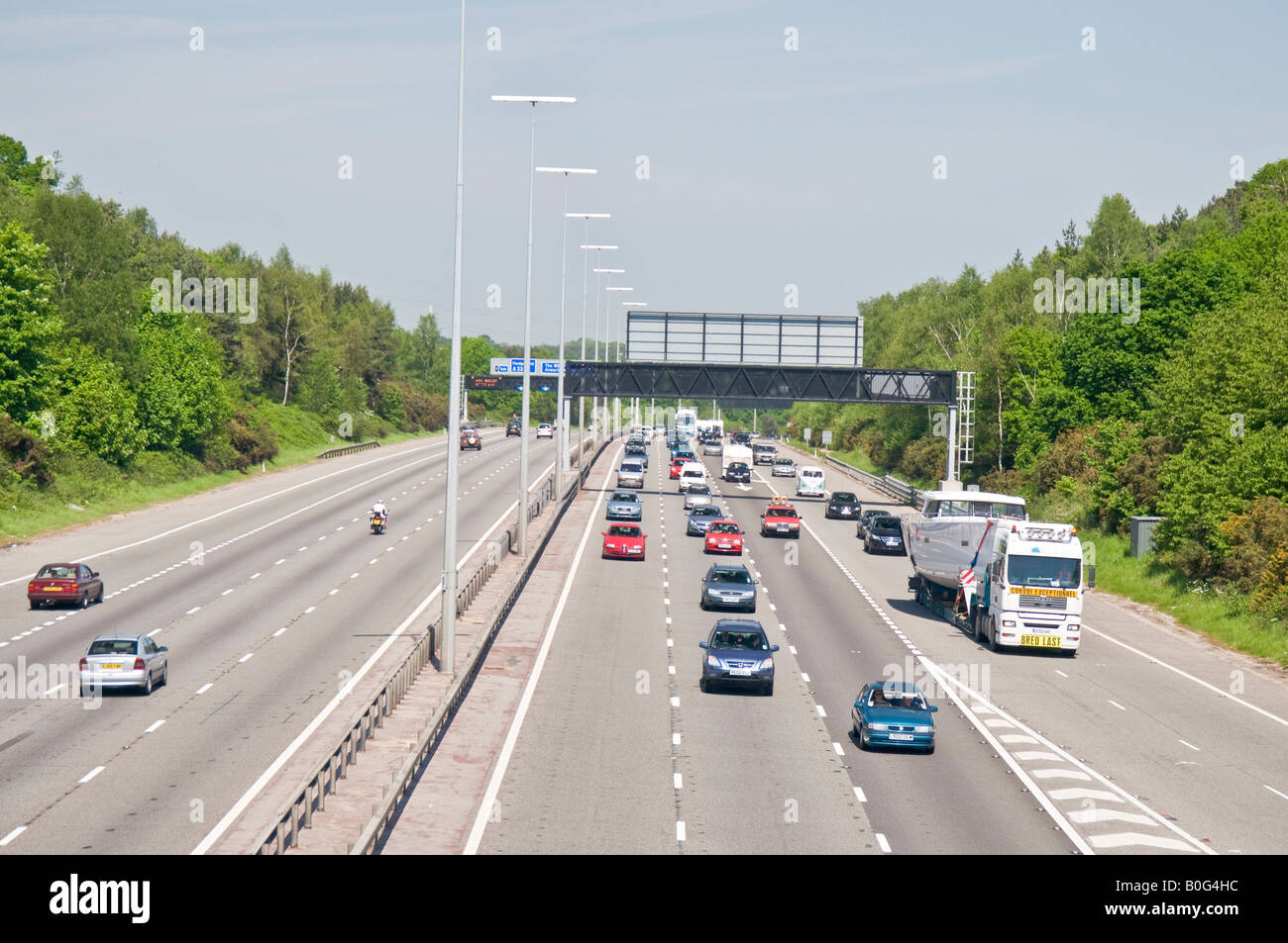 Le trafic sur l'autoroute M27, près de Southampton en Angleterre un jour normal montrant divers signes de marquage au sol et de portiques etc. Banque D'Images