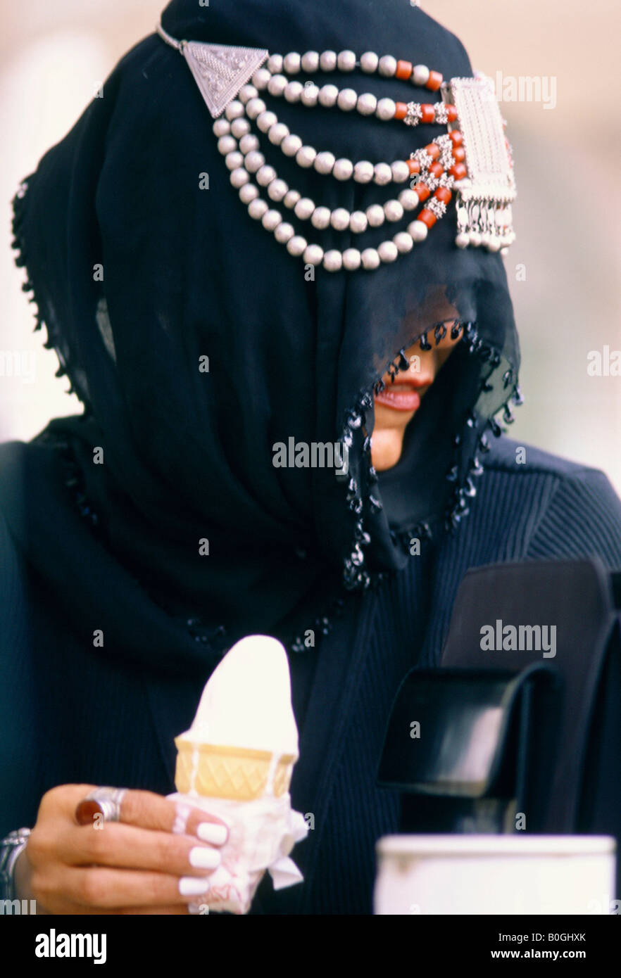 Une femme voilée de manger un cornet de crème glacée de fusion, la Jordanie. Banque D'Images