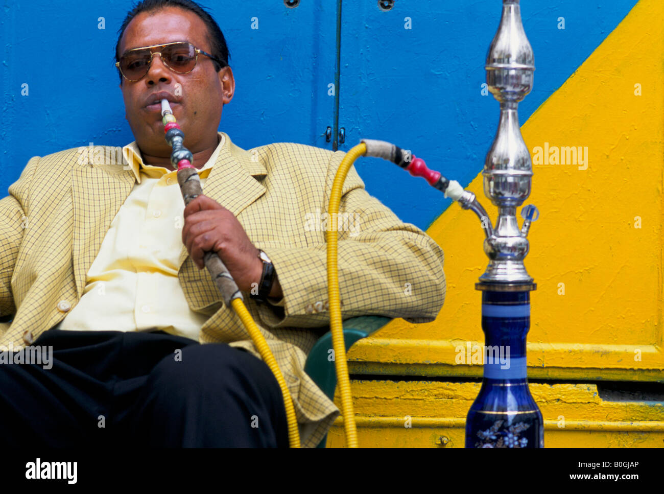 Un homme d'âge moyen assis fumant un narguilé à Tripoli, Libye. Banque D'Images