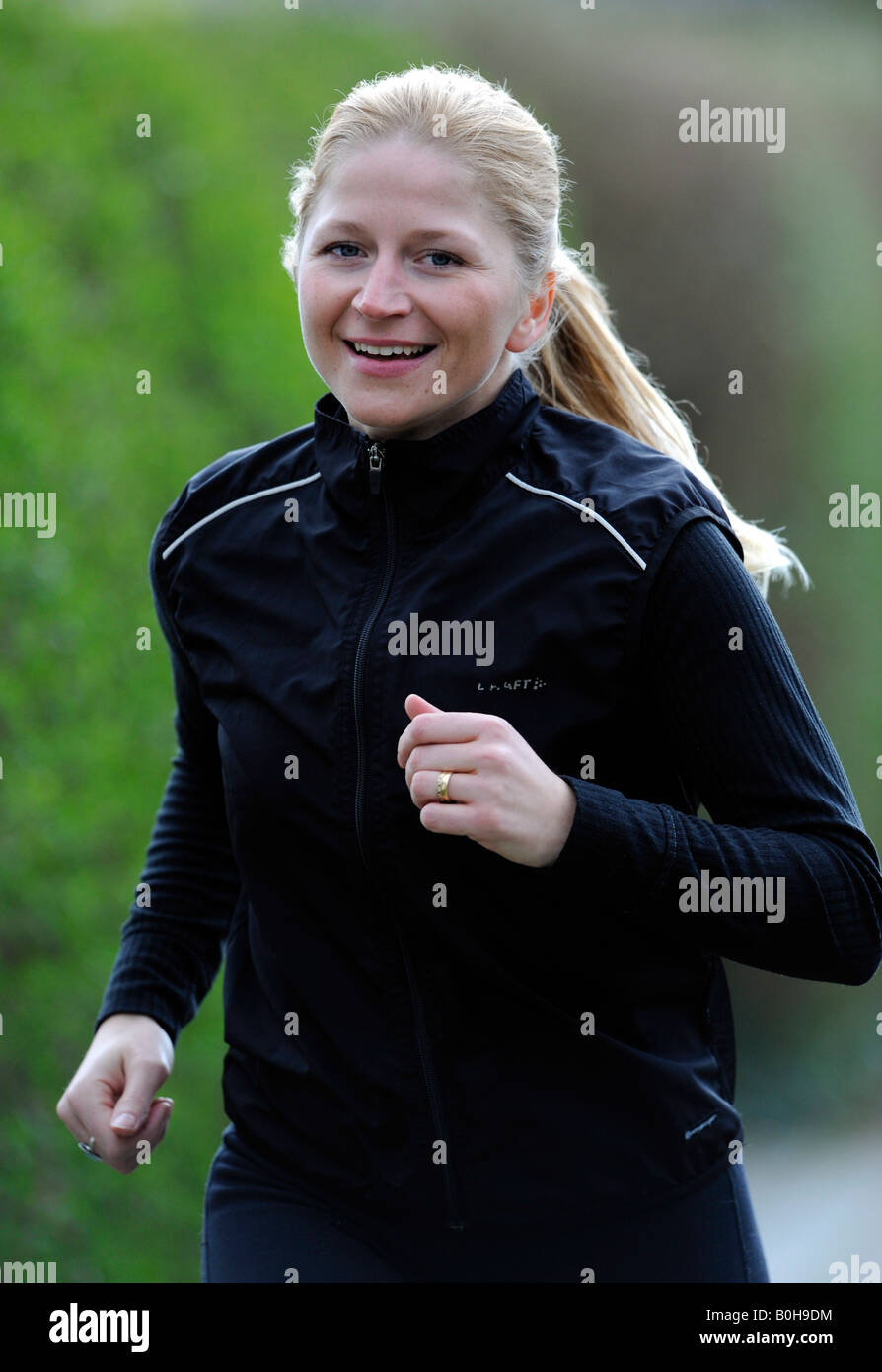 Les jeunes, smiling blonde woman jogging survêtement noir Banque D'Images