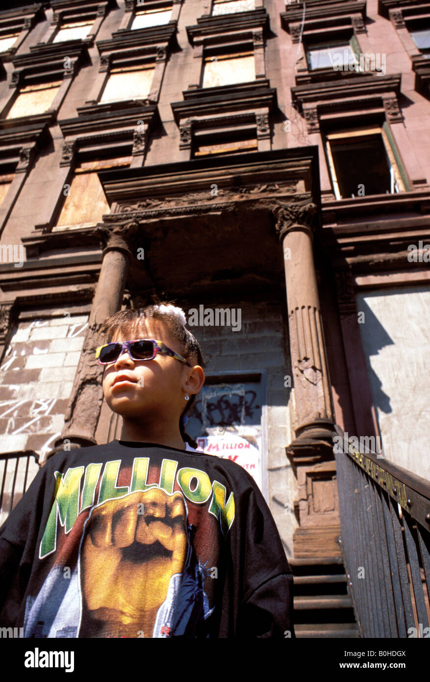 Une petite fille à lunettes l'extérieur d'un immeuble à Harlem, New York City, New York, USA. Banque D'Images