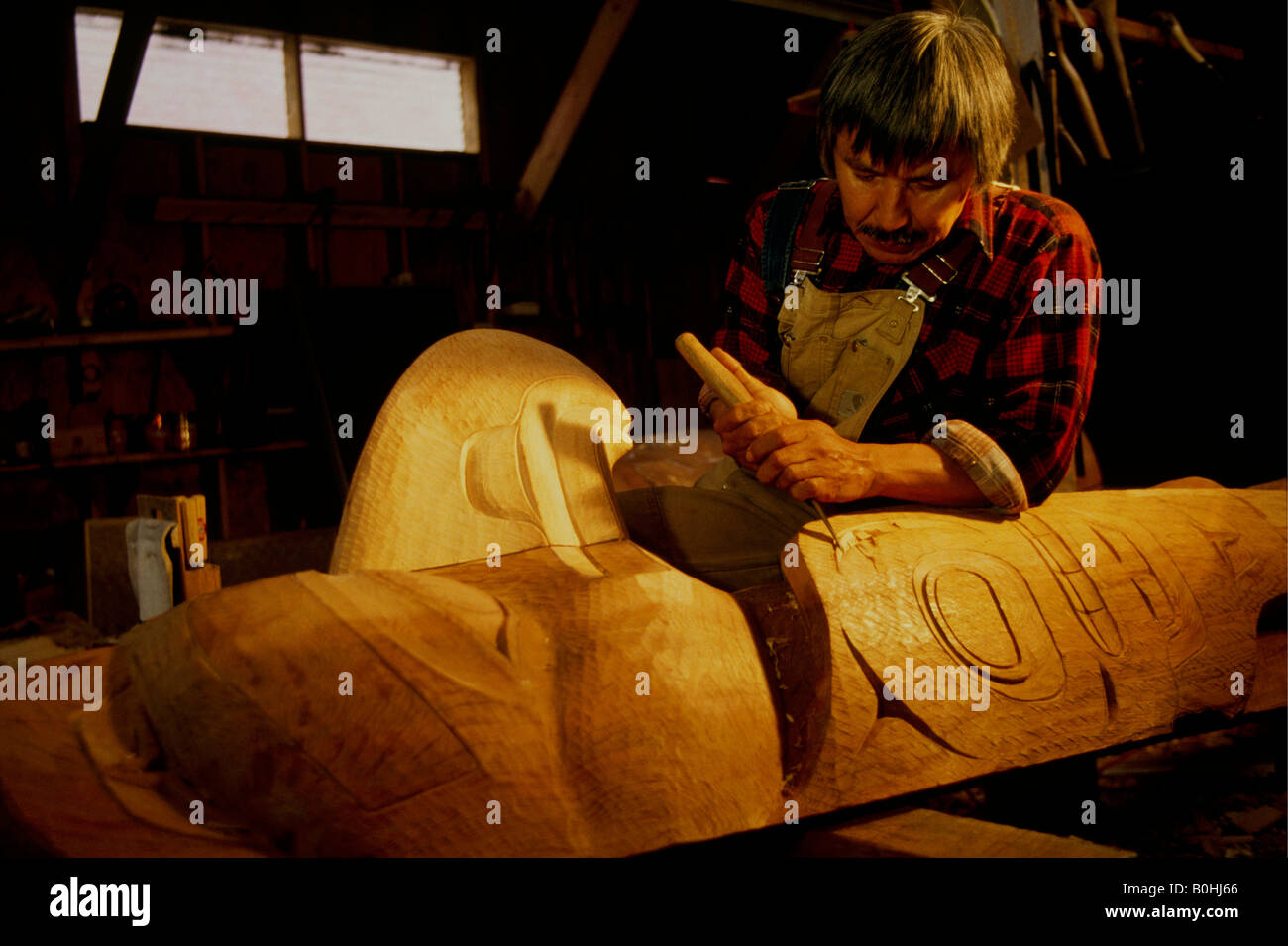 Un homme indien tlingit d'Alaska sculpte un totem à l'Saxman totem park, Ketchikan, Alaska, USA. Banque D'Images