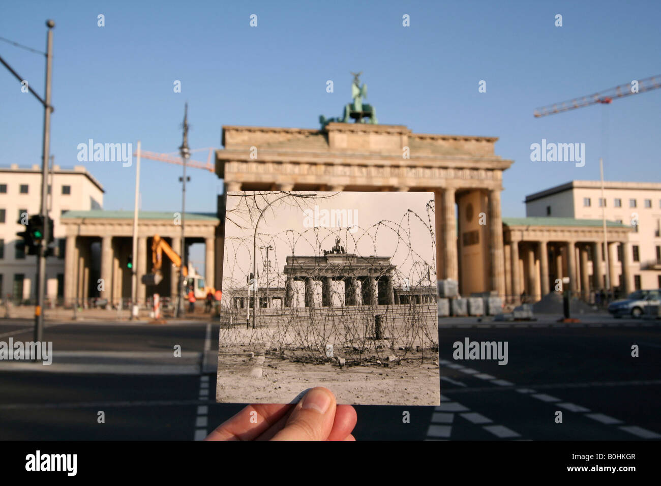 Hier et aujourd'hui, main tenant une vieille photo en noir et blanc de Brandenburger Tor ou Porte de Brandebourg montrant le mur de Berlin et ba Banque D'Images