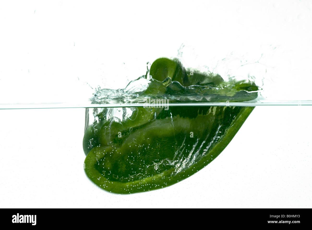 La moitié d'un poivron vert tomber à l'eau Banque D'Images