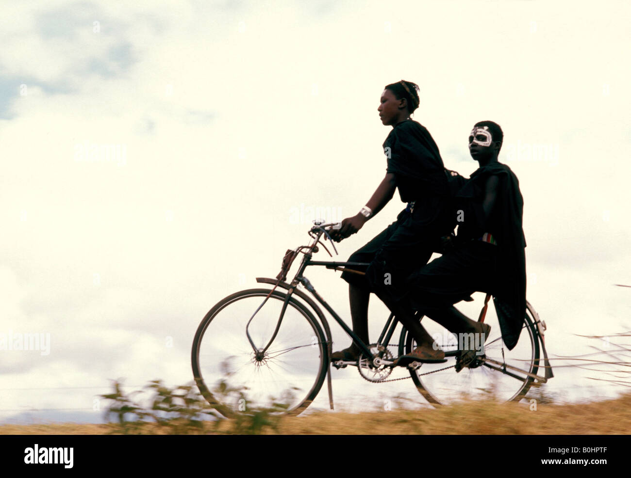 Deux jeunes hommes Masai équitation sur une bicyclette, en Tanzanie. Banque D'Images