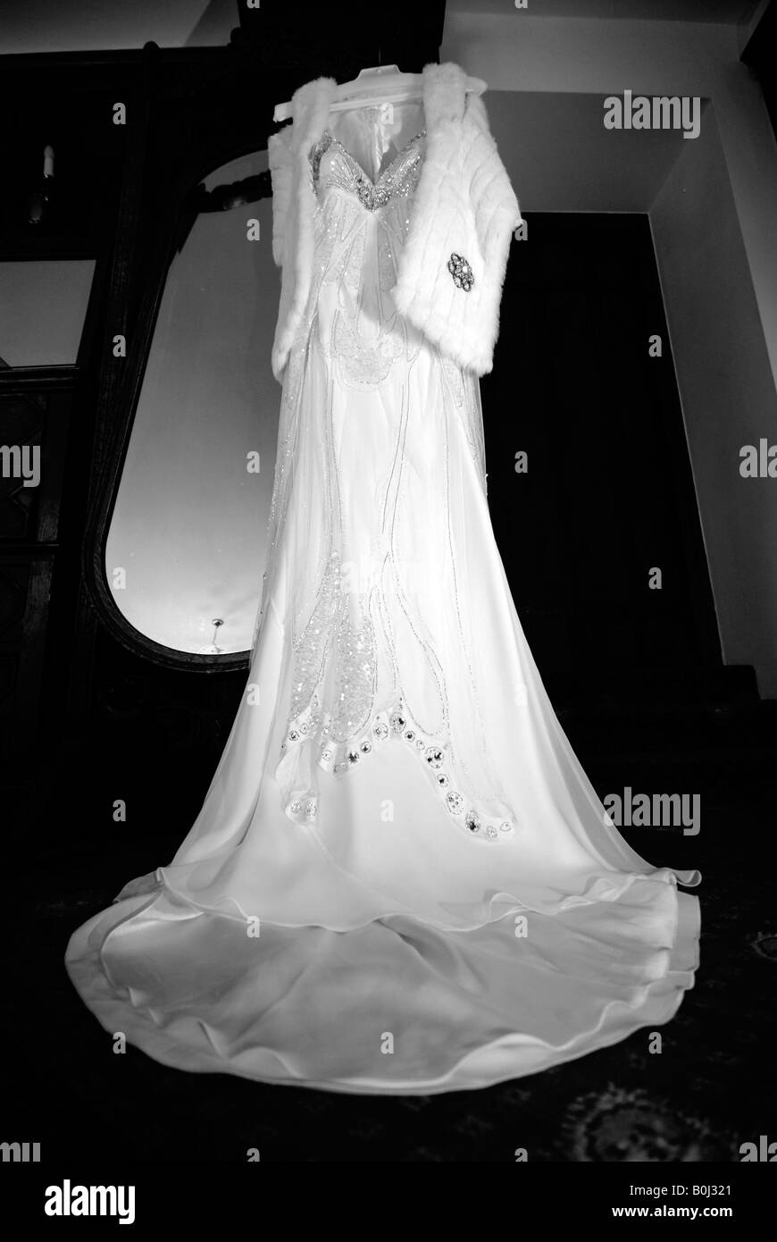 Une robe de mariage pendaison devant un miroir dans la chambre d'hôtel avant son mariage. Banque D'Images