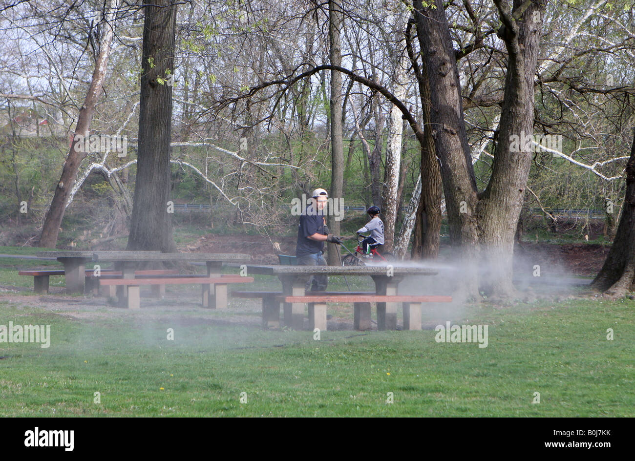 Un employé du parc d'une puissance de lavage d'une table de pique-nique du parc. Banque D'Images