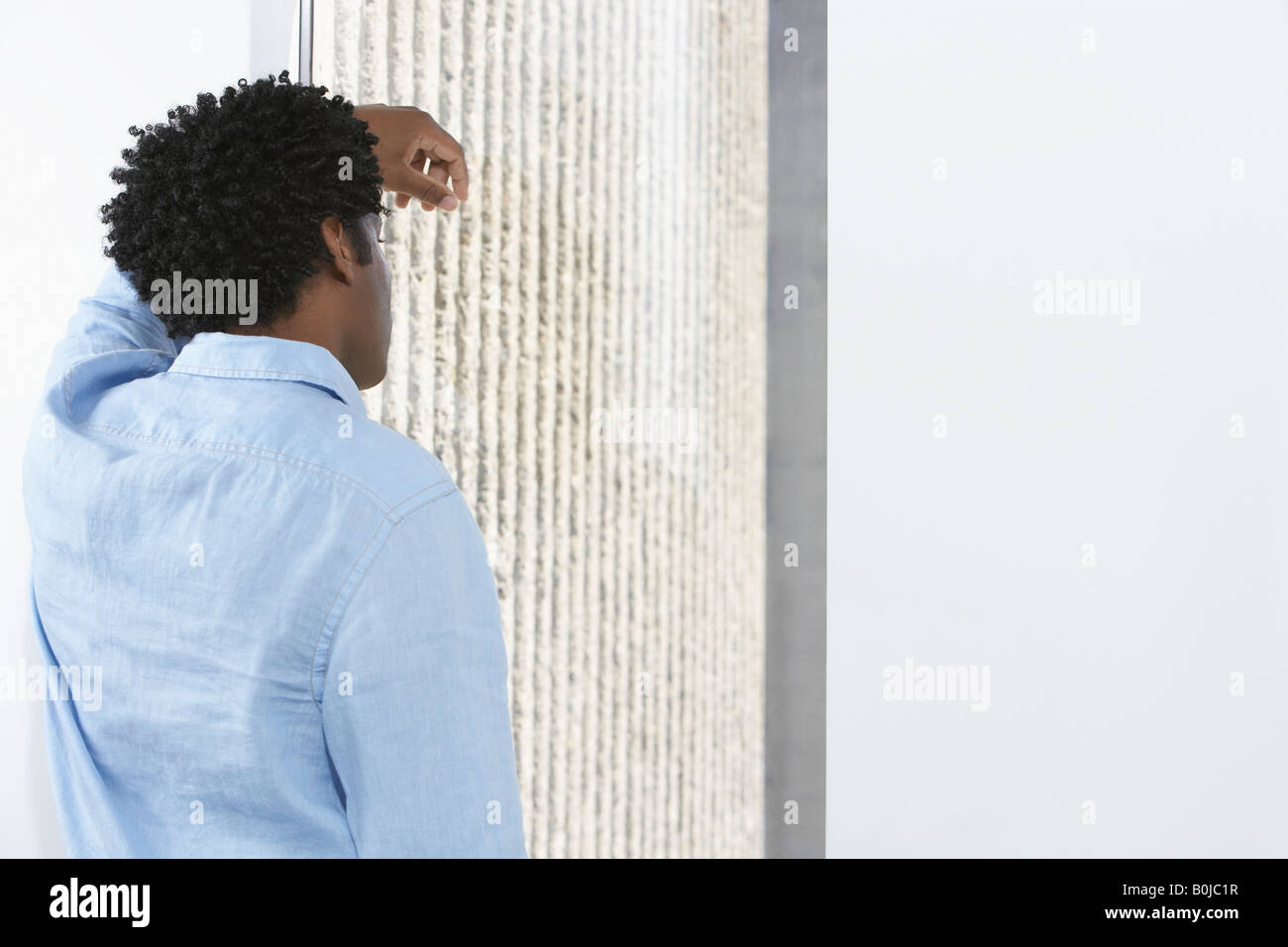 Business man leaning against wall, à l'intérieur Banque D'Images