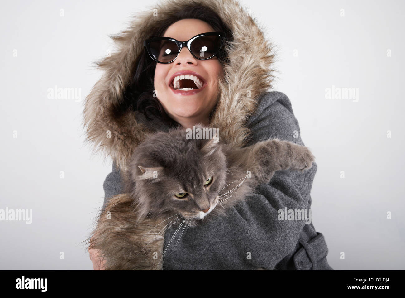 Femme portant manteau à capuchon, holding cat, rire Banque D'Images