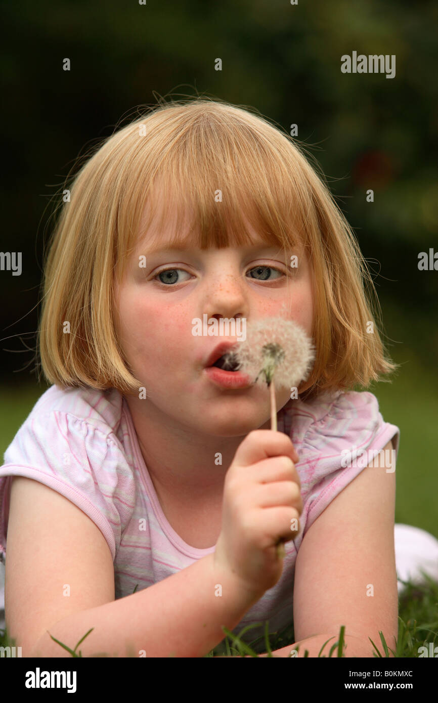 Enfant soufflant un pissenlit Banque D'Images