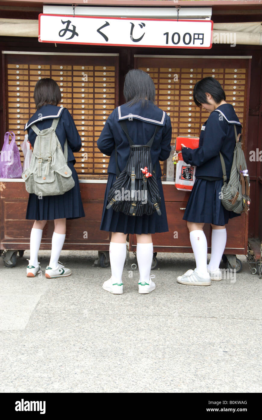 Juniour supérieur ou moyen School girls visiter Asakusa sur leur voyage scolaire lire Mikuji ou temple fortune tiré au sort. Banque D'Images